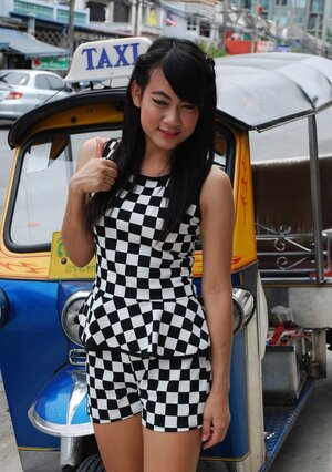 Inviting Thai performer in a checkered dress gets into the Tuk Tuk Taxi