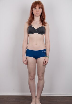 Lady with red hair and colored rose tattooed on pale body strips down