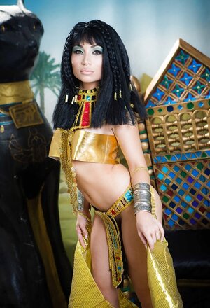 Far eastern girl plays the role of Cleopatra posing on a golden throne