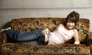 Japanese porn model poses on camera wearing a pink top and bell-bottom jeans