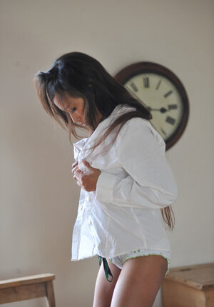 Playful schoolgirl removes uniform to expose undressed body while lying on the desk